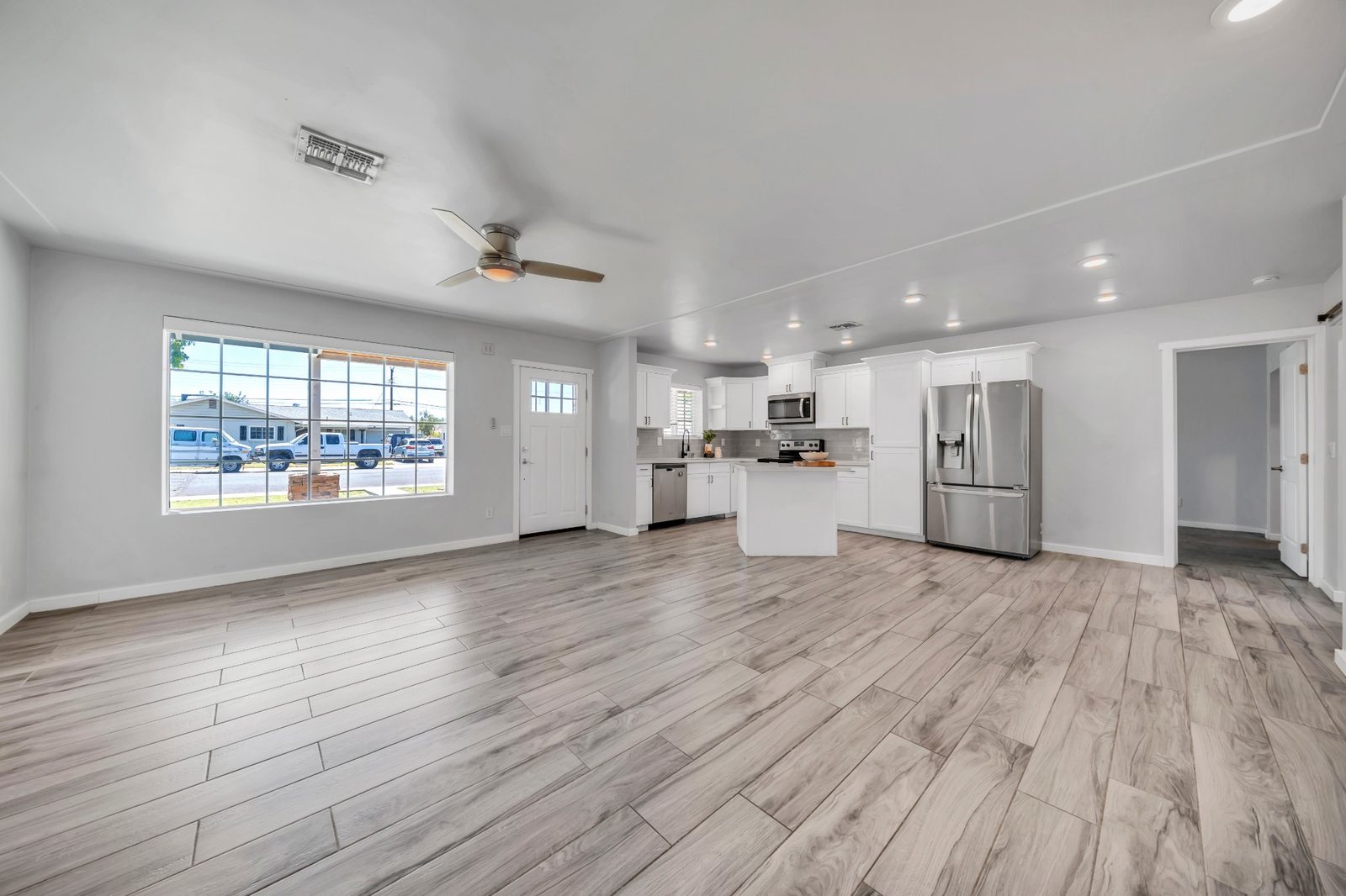 Open living area looking through to the kitchen, with wood-look tile running throughout