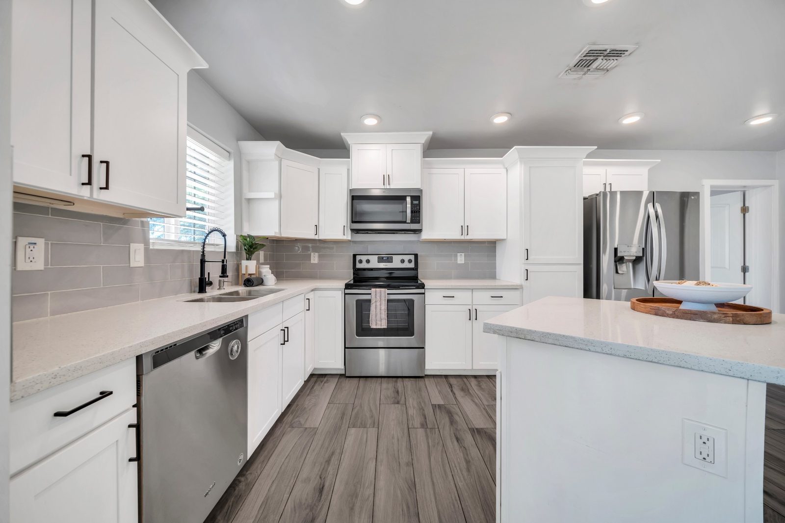 Kitchen with a quartz island, white shaker cabinets and stainless appliances