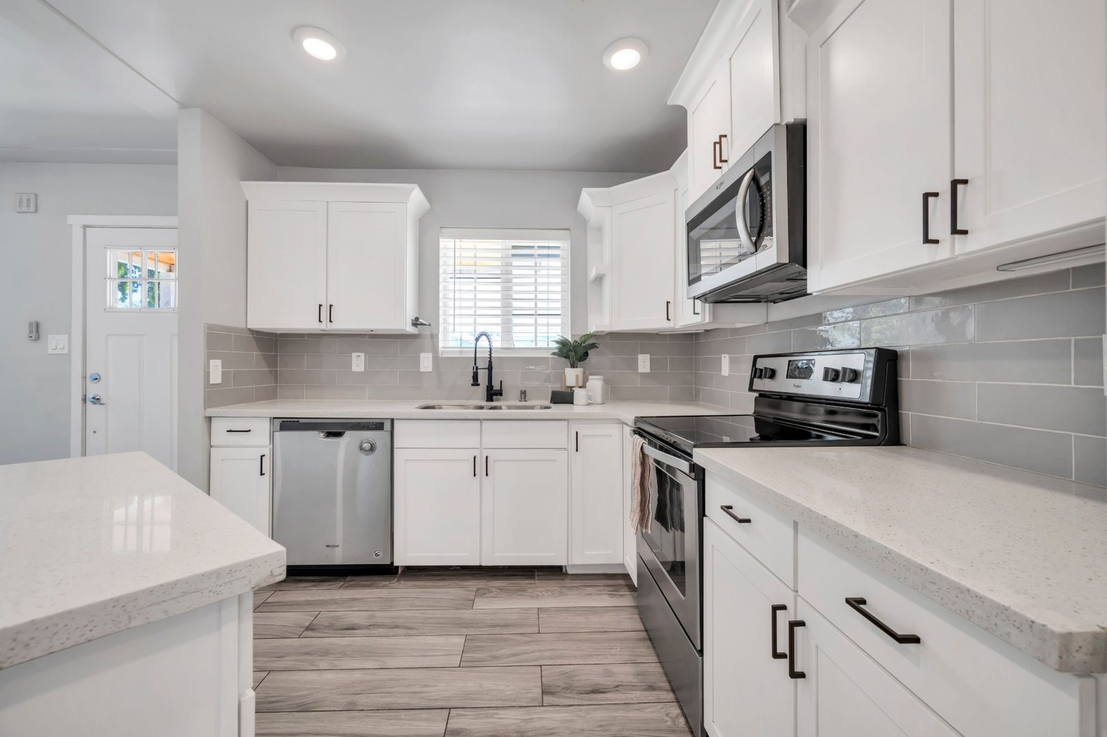 Kitchen range and microwave against a grey tile backsplash, with the pantry cabinet alongside