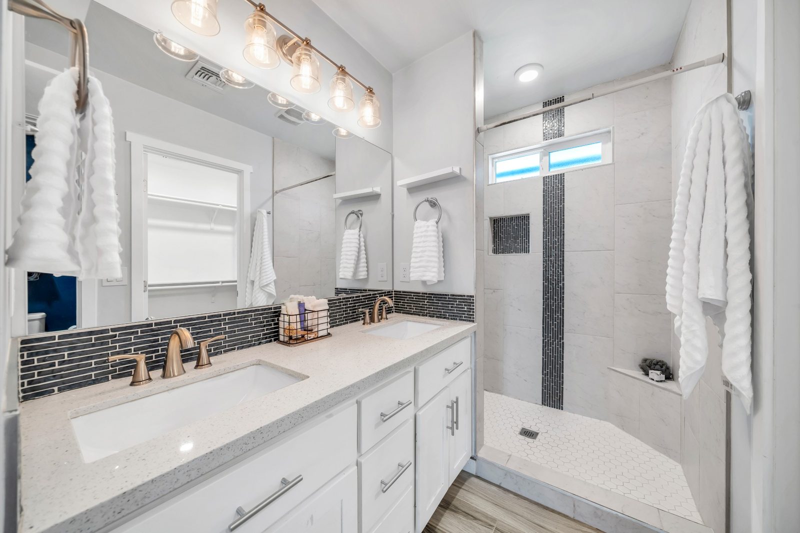Primary bathroom with a double quartz vanity and a tiled walk-in shower