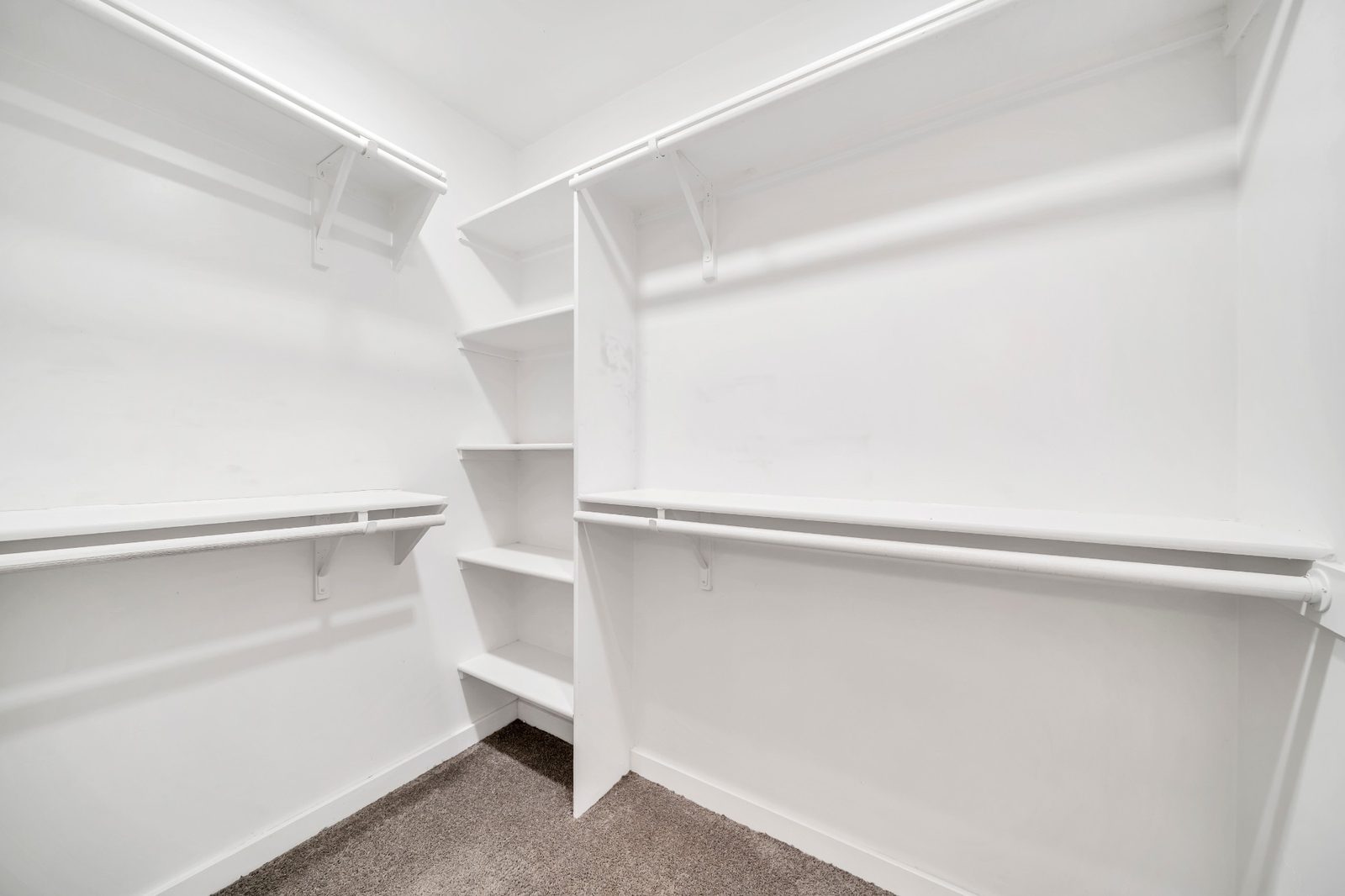 Walk-in closet fitted out with hanging rails and shelving on three walls