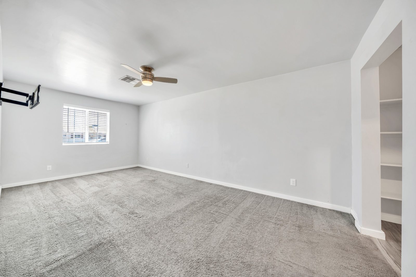 Third carpeted bedroom with a ceiling fan and a built-in shelving nook
