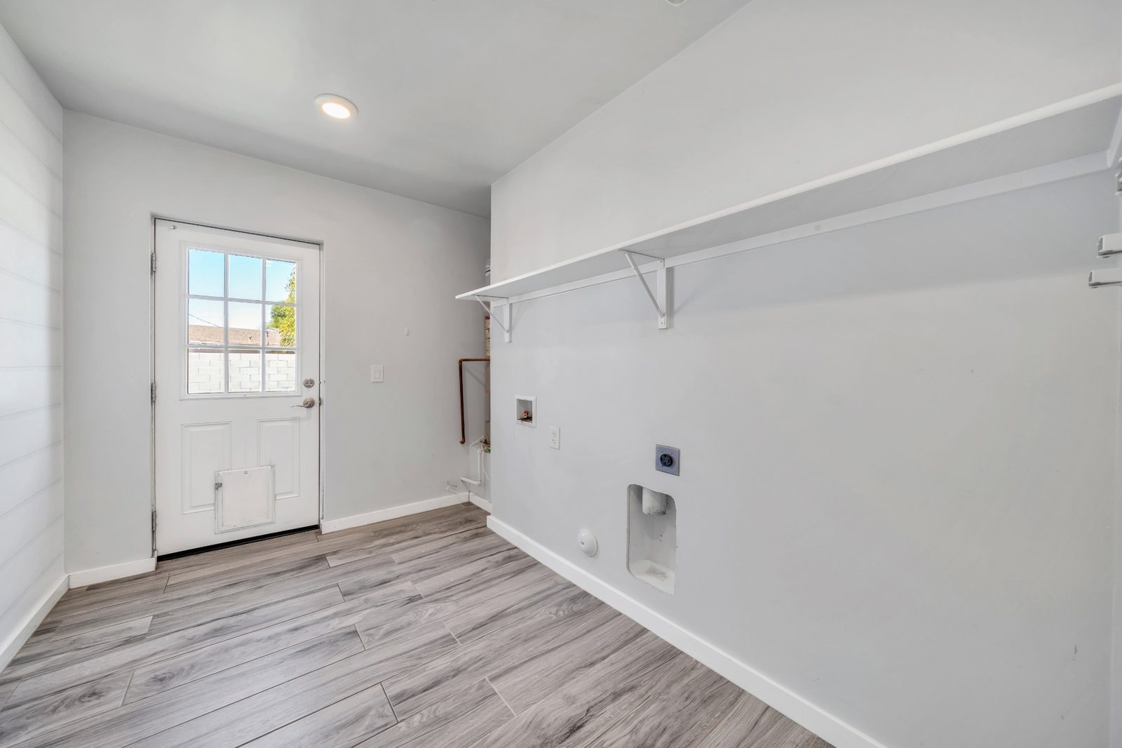 Separate laundry room with washer and dryer hookups, shelving and a door to the back yard